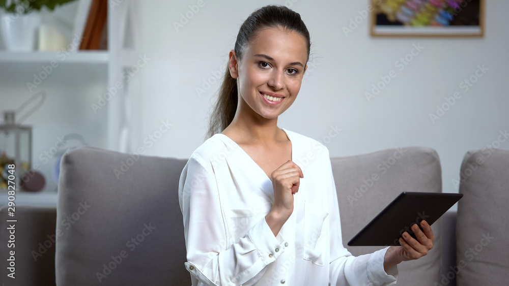 Young woman using tablet PC at home, looking at camera, social network, online Young woman using tablet PC at home, looking at camera, social network, online