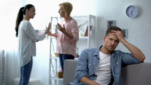 Cuadro en lienzo Exhausted male listening wife and mother-in-law arguing at home, rivalry