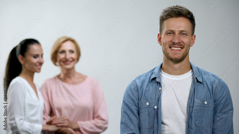 Woman and mother-in-law holding hands, admiring male in family, relations Woman and mother-in-law holding hands, admiring male in family, relations