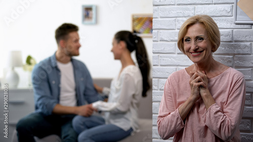 Happy smiling mother-in-law watching young couple reconciliation after quarrel