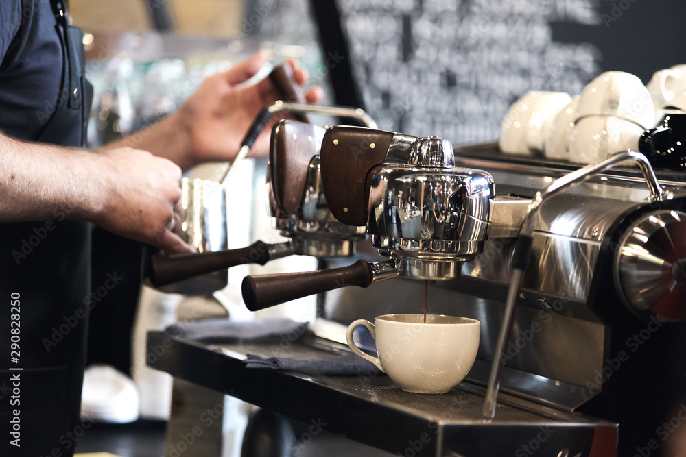 Barista making cappuccino with espresso machine in cafe.
