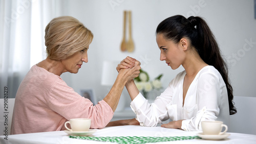 Mother and daughter-in-law looking on each other during arm wrestling battle