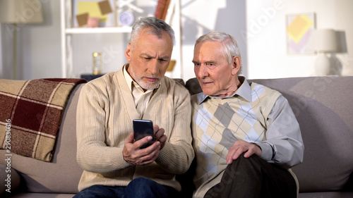 Senior male showing new smartphone elderly friend, using modern technology