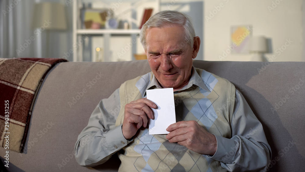Depressed crying pensioner holding photo, old age loneliness, nostalgia sadness