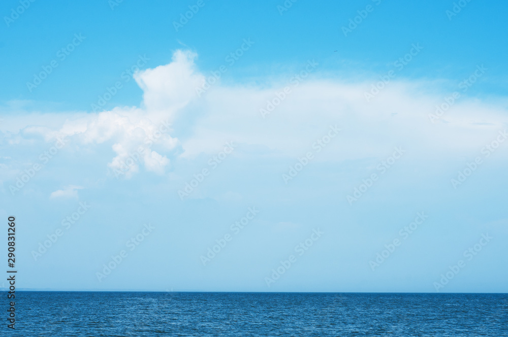Beautiful seascape panorama. Сalm sea and blue sky with clouds.
