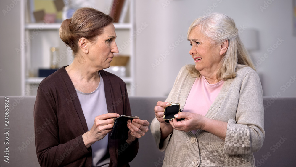 Aged female friends complaining poverty problems showing empty wallets, crisis Aged female friends complaining poverty problems showing empty wallets, crisis