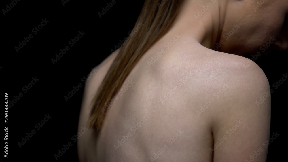 Naked woman turned from camera, black background, fighting insecurities concept Naked woman turned from camera, black background, fighting insecurities concept
