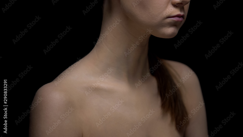 Naked female standing against black background, fighting insecurities concept Naked female standing against black background, fighting insecurities concept