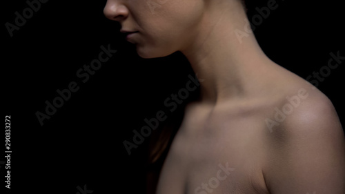 Naked female standing against black background, harassment victim, kidnapping