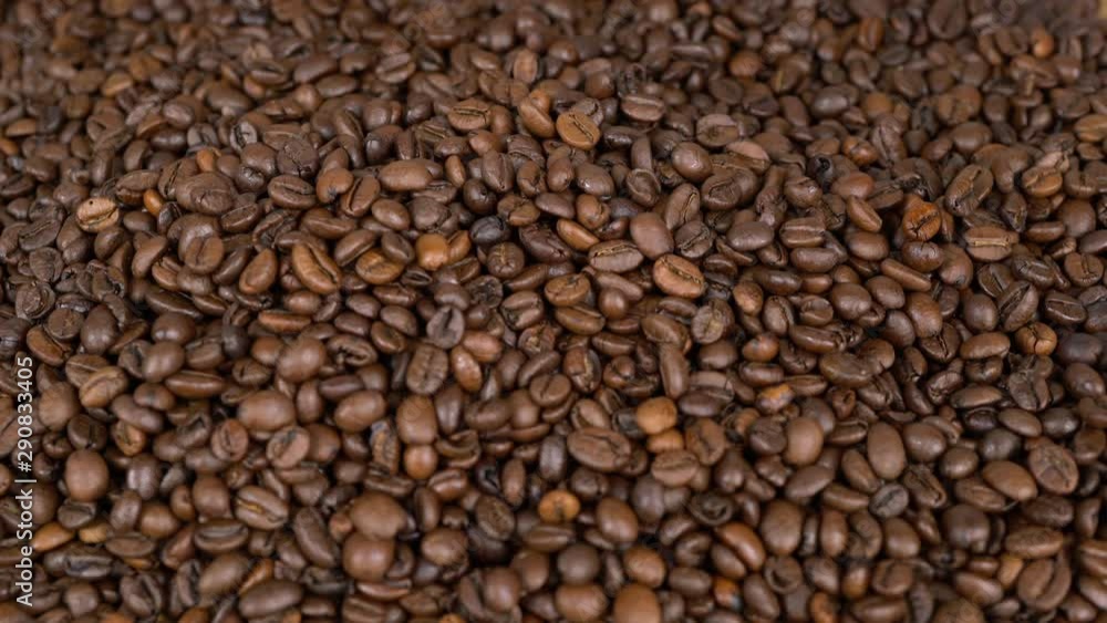 Close up hand throwing coffeebeans on a big pile Close up hand throwing coffeebeans on a big pile