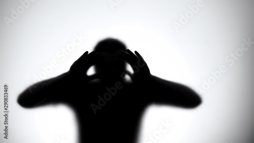 Silhouette of male thief looking through door glass, break in empty house