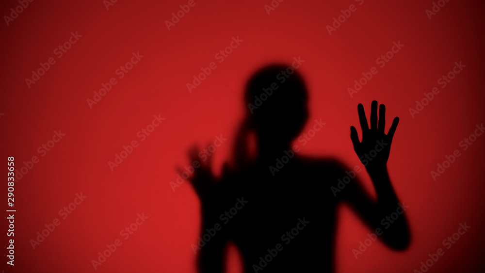 Female silhouette behind glass escaping from danger, red lights on background
