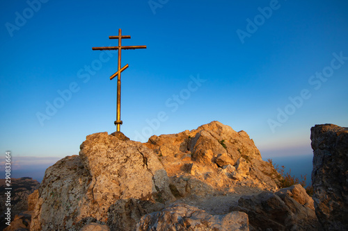 Religious cross on the mountain. Blue sky and mountains.