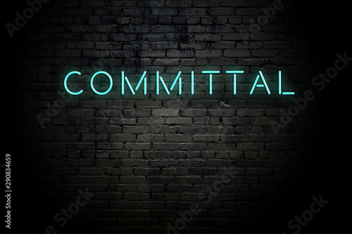 Highlighted brick wall with neon inscription committal