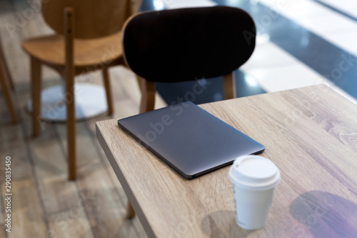 A dark laptop on the light wood table