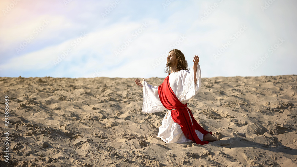 Righteous man kneeling in desert, praying to god with raised hands, confession Righteous man kneeling in desert, praying to god with raised hands, confession