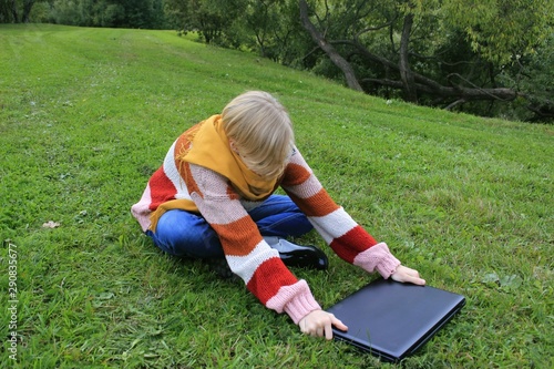 young woman lies on grass with laptop