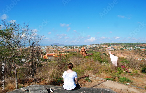 A traveler girl sitting on bunker and enjoying view of Cham Towers and surrounding, Vietnam 