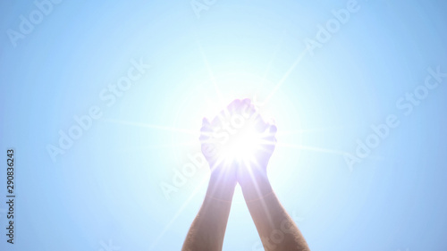 Photography Hands holding sacred light against blue sky, religious miracle, ray of hope