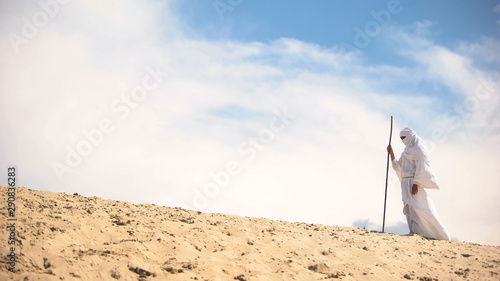 Photography Lost Bedouin with staff walking in hot desert, climate change, hopelessness