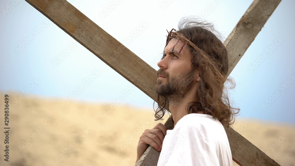 Jesus Christ with crown of thorns carrying cross, praying to God for sinners - obrazy, fototapety, plakaty 