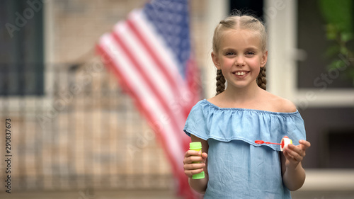 American little girl holding soap bubbles on backyard, carefree childhood, fun