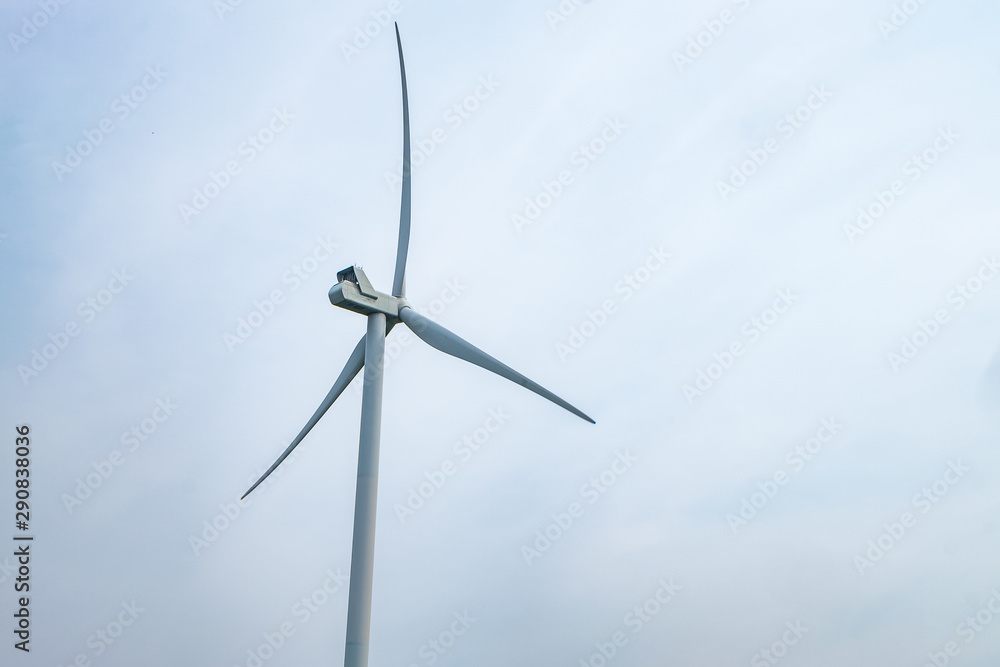 rotating blades of a windmill propeller on blue sky background. Wind power generation. Pure green energy.