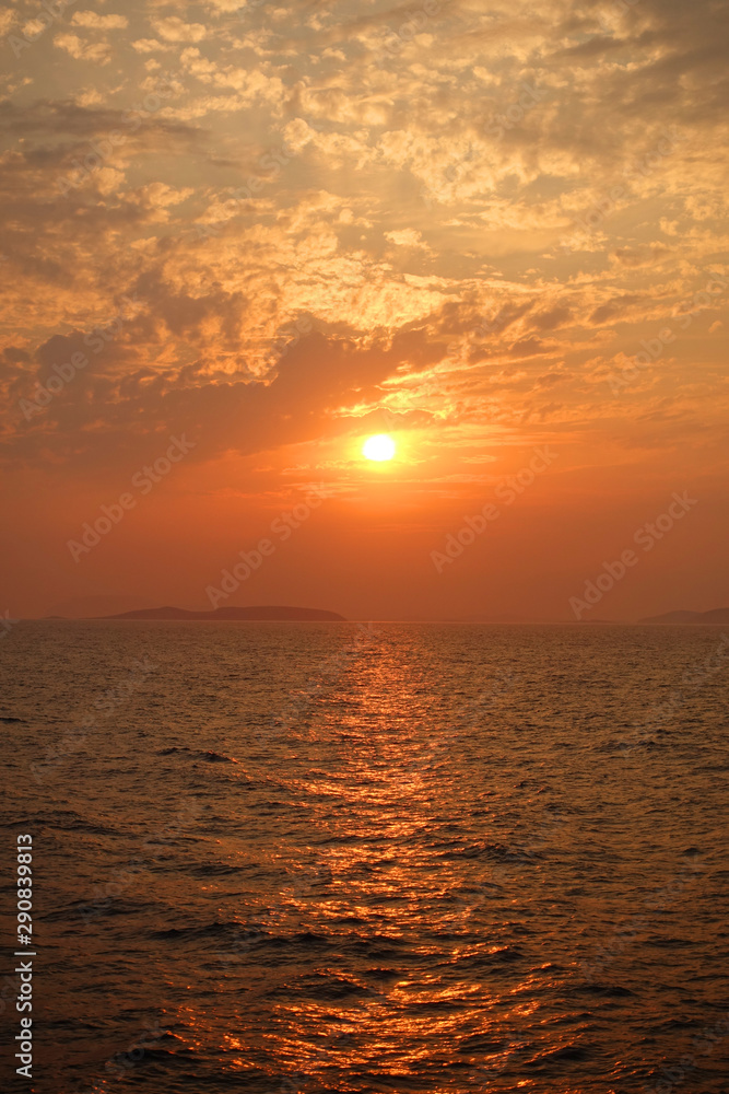 Beautiful sunset over Aegean sea with some clouds and golden colours