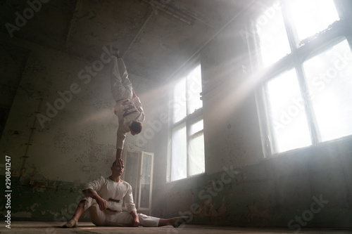 Billede på lærred Male duo making acrobatic tricks wearing costume of insane people in abandoned r