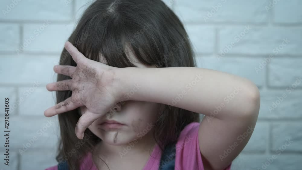 Child abuse. Sad dirty girl covers her face with her hand ...   