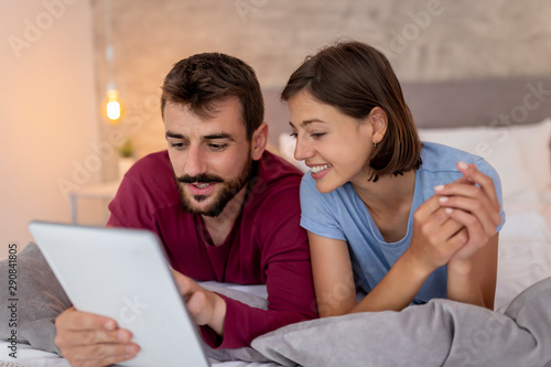 Couple lying in bed and using tablet computer
