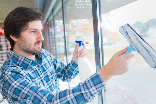man cleaning the windows in a shop