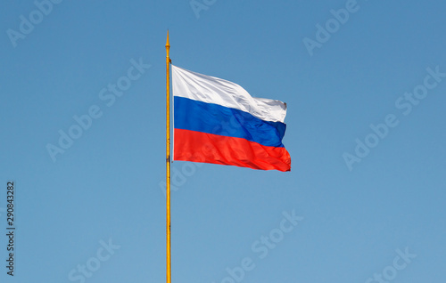 Russian flag waving on the wind against blue sky