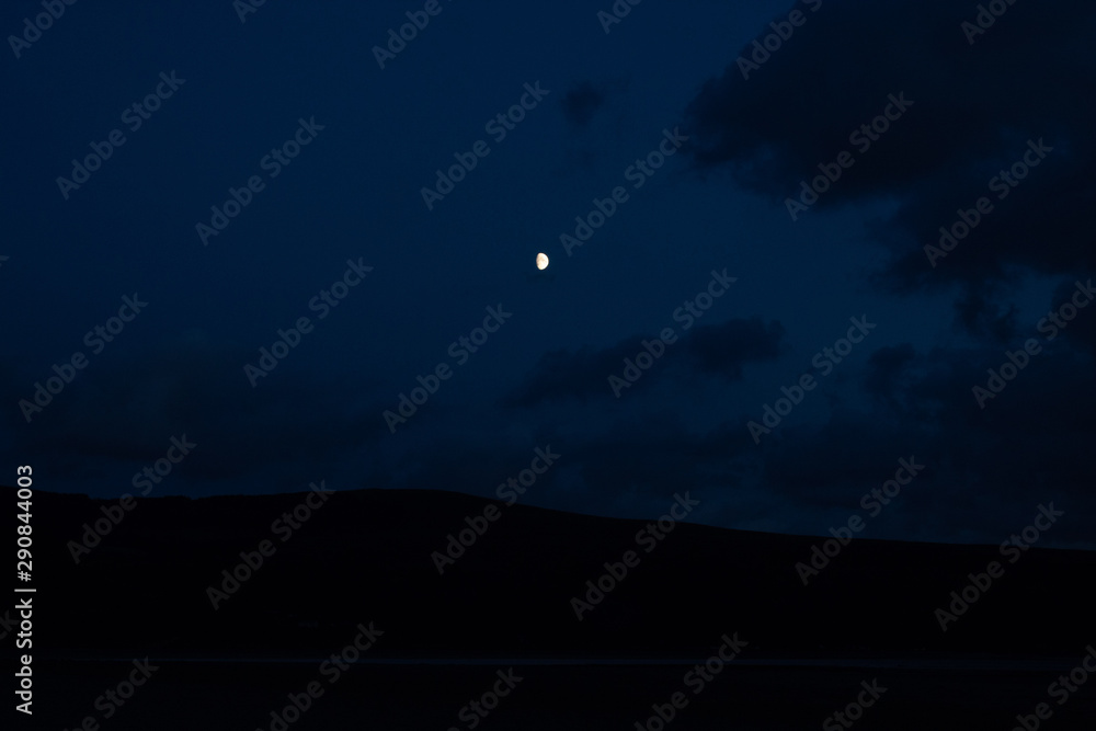 Moon with clouds over hill