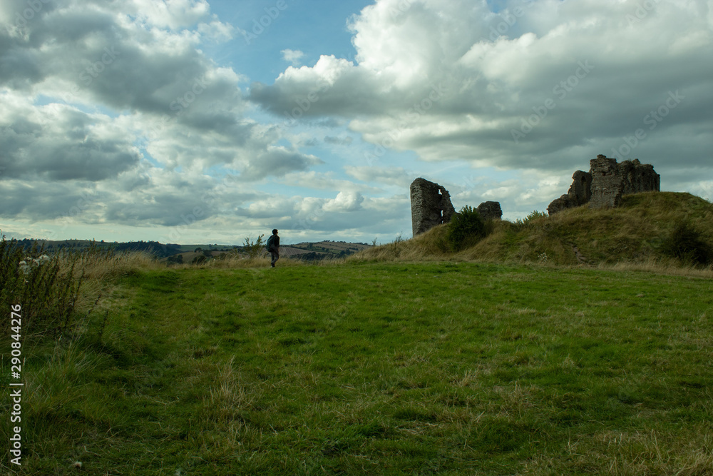 Ruins and hiker at green field