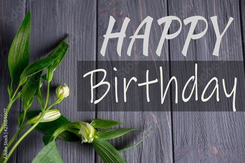 Greeting card with the inscription happy birthday. Congratulatory greeting to the girl, mother with flowers and a gift on a wooden background. Alstroemeria flowers