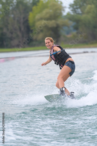 young pretty woman riding wakeboard on wave