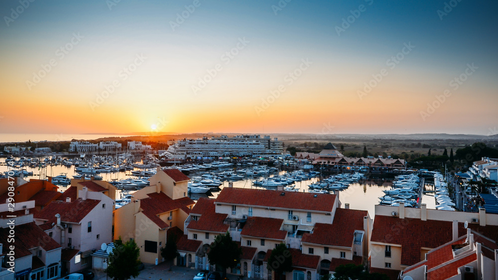 High perspective view of sunset at Vilamoura Marina, Algarve, Portugal with busy nightlife around the Marina full of shops and restaurants