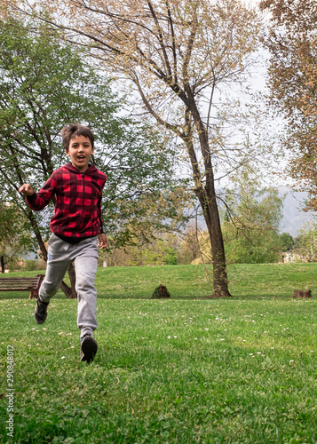 Happy smiling boy in casual clothes running in the park.