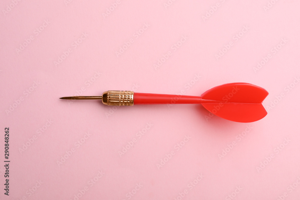 Red dart arrow on pink background, top view Red dart arrow on pink background, top view
