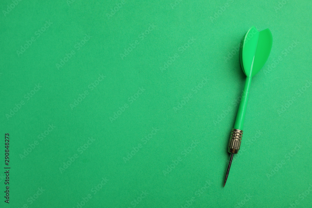 Plastic dart arrow on green background, top view with space for text Plastic dart arrow on green background, top view with space for text