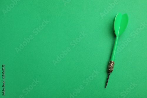 Plastic dart arrow on green background, top view with space for text