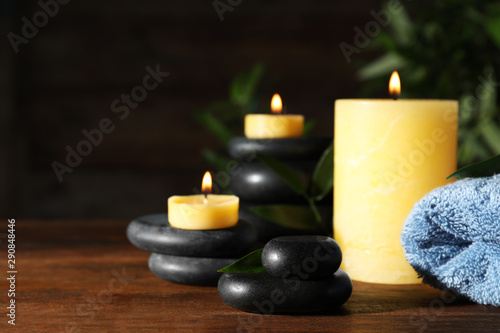 Composition with candles and spa stones on wooden table. Space for text