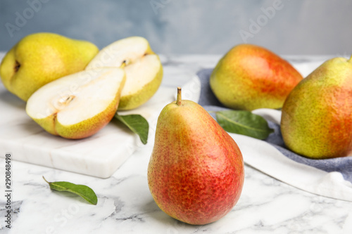 Ripe juicy pears on marble table against blue background