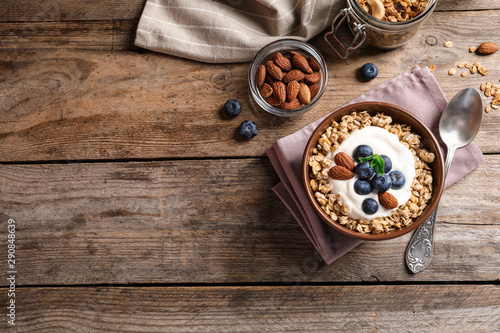 Bowl of tasty oatmeal with blueberries and yogurt on wooden table, flat lay. Space for text
