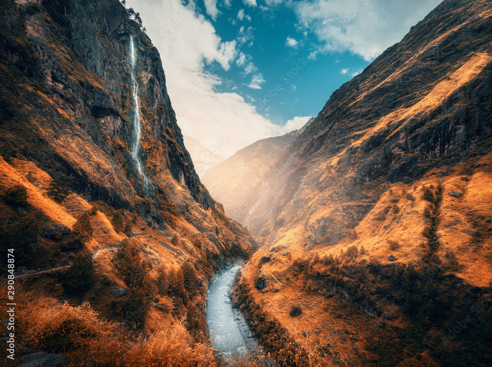 Fototapeta Beautiful mountains covered orange grass in autumn. Colorful landscape with mountain valley, river, waterfall, meadows and forest, sky with clouds in fall at sunset. Travel in Himalayas. Nature