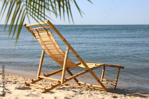 Sandy beach with empty wooden sunbed on sunny day