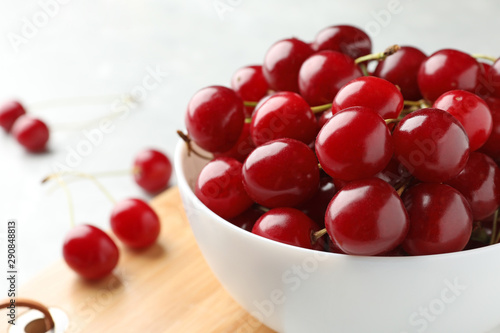 Bowl of tasty ripe cherries on board, closeup