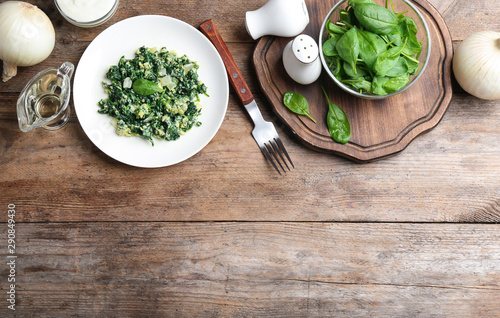 Flat lay composition with cooked spinach and space for text on wooden table. Healthy food