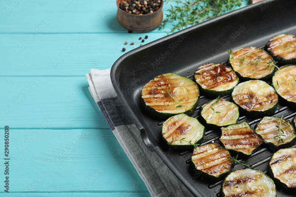 Grill pan of delicious zucchini slices on blue wooden table, closeup. Space for text